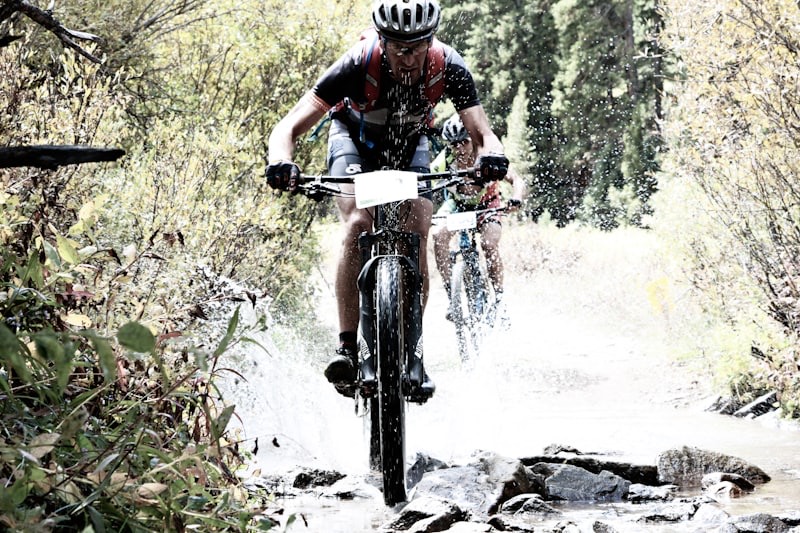 Mountain biker splashing through a rocky stream crossing