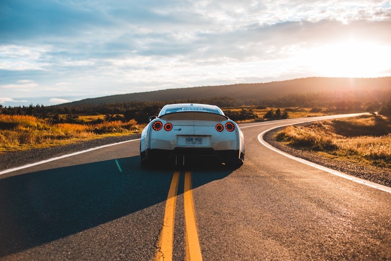 Sports car driving a winding road at sunset