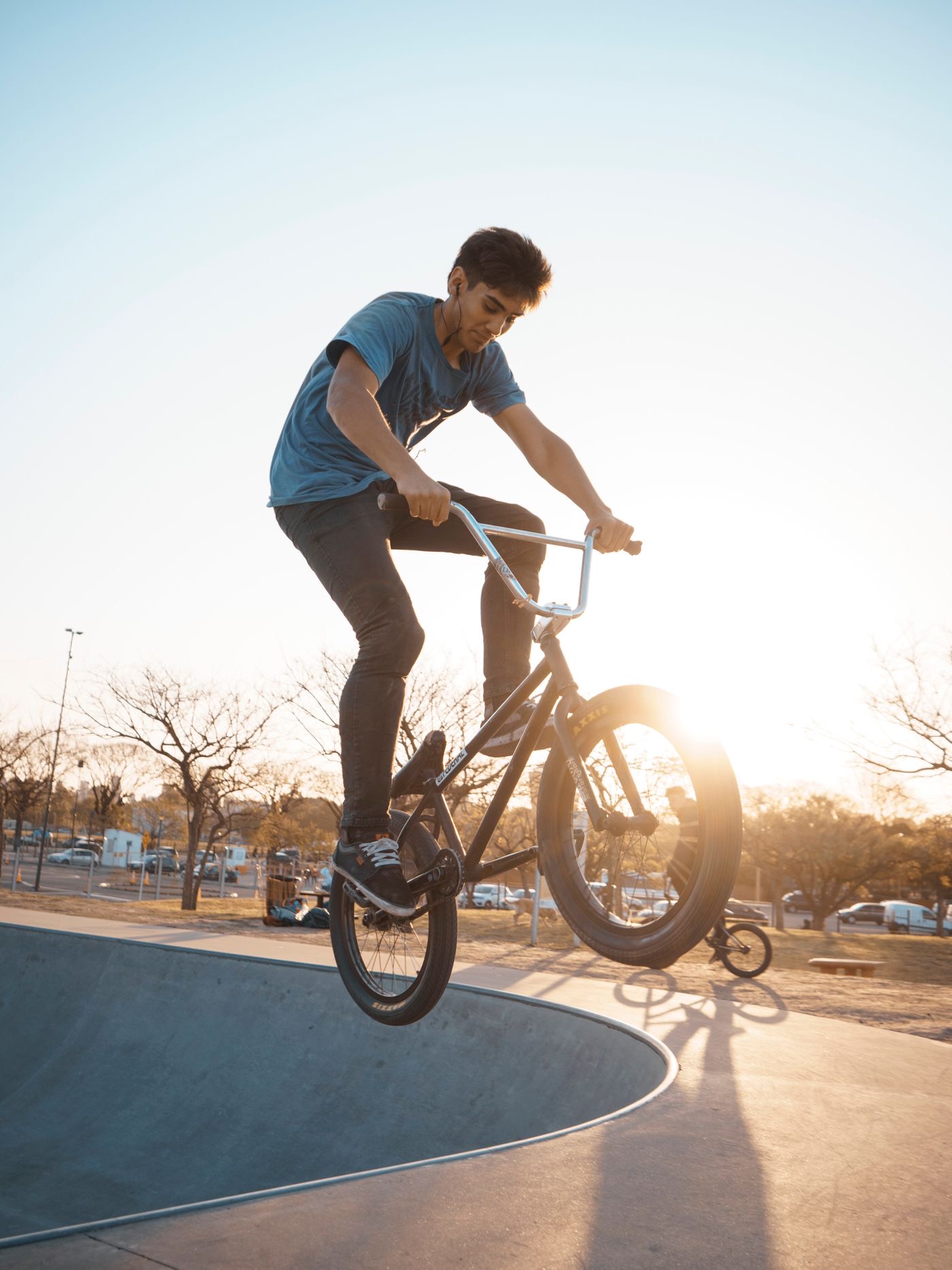 BMX rider jumping a skatepark bowl at sunset